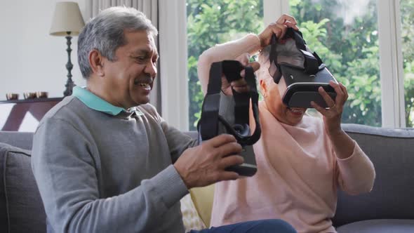 Happy mixed race senior couple wearing vr headset and having fun at home