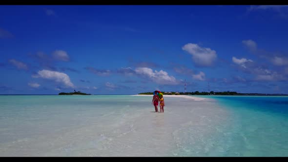 Family of two engaged on paradise island beach wildlife by blue sea with white sand background of th