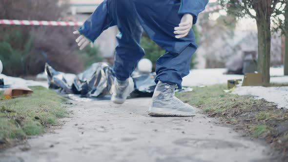 Back View Woman in Uniform and Protective Shoes Walking to Corpse at Crime Scene Gathering Equipment