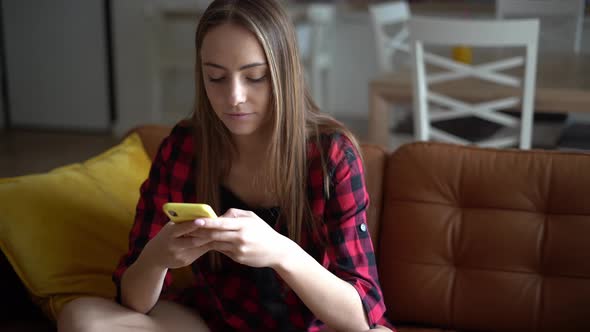 Beautiful young woman writing text message on her smartphone