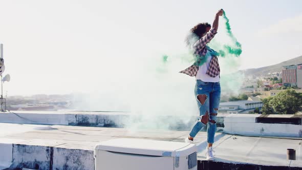 Fashionable young woman on urban rooftop using a smoke grenade
