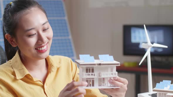 Close Up Asian Woman Holding And Looking At Model Of A Small House With Solar Panel