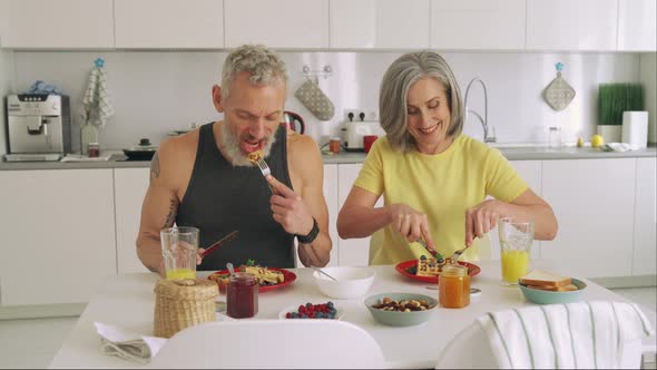 Happy Healthy Fit Mature Senior Family Couple Having Breakfast Sit at Kitchen