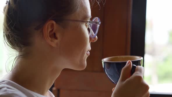 Adult woman in glasses sipping hot coffee