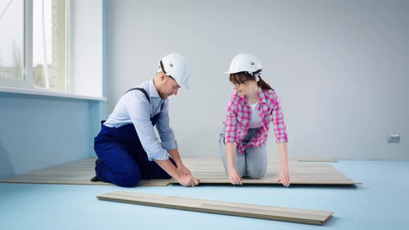 Team of Man and Woman Laying Laminate Knitting Locks and Giving Five to Each Other While Renovating