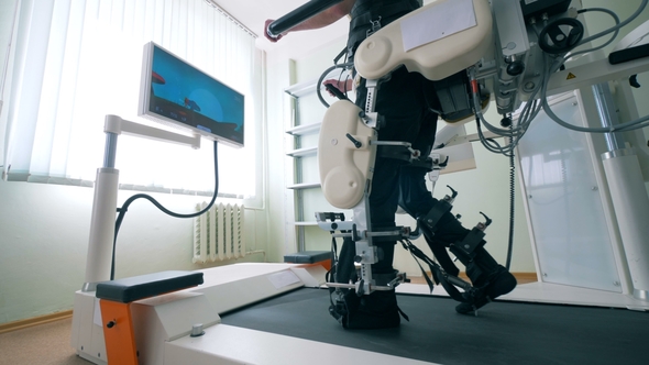 Modern Medical Recovery Device. Disabled Man Is Training To Walk with the Help of a Simulation