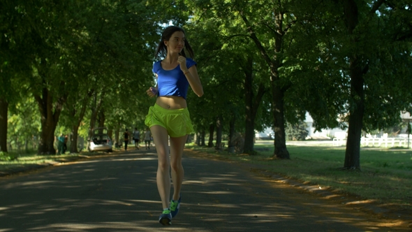 Smiling Beautiful Sporty Woman Jogging in Park