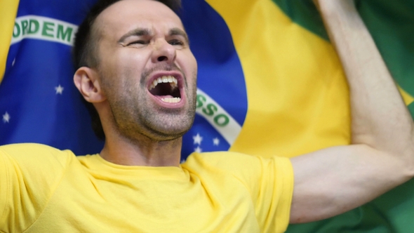 Brazilian Fan Celebrating While Holding the Flag of Brazil