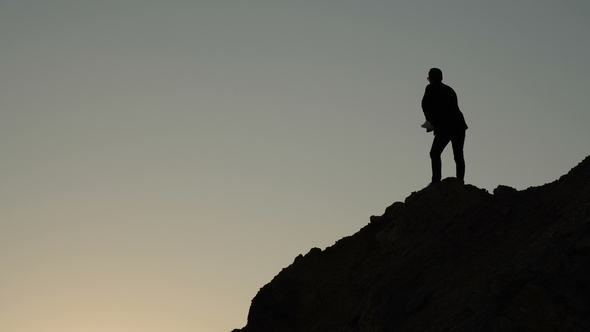 Silhouizes a Business Man Who Throws Documents Off the Cliff