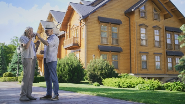 Happy Senior Couple Showing Keys To New Big House