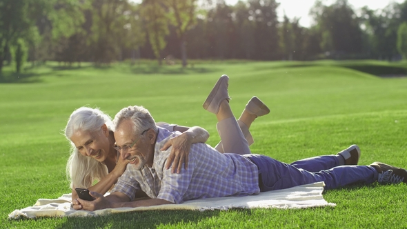 Gorgeous Senior Couple Using Mobile Phone Outdoors