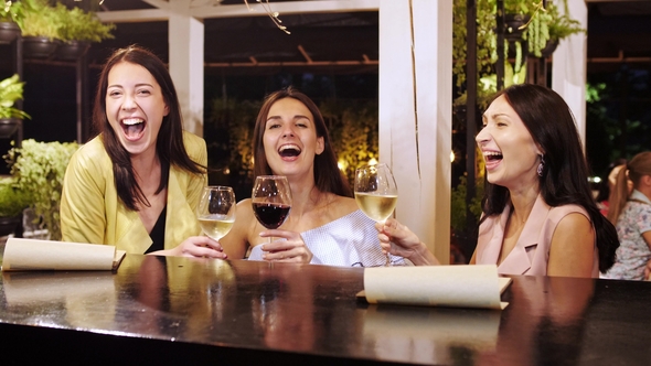 Three Pretty Girls Are Clink Glasses with Drinks at the Bar.