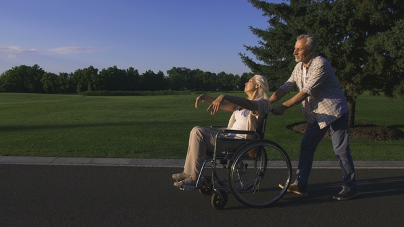 Man with Wife in Wheelchair Enjoying Outdoors