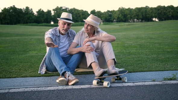 Stylish Senior Couple Sitting with a Skateboard