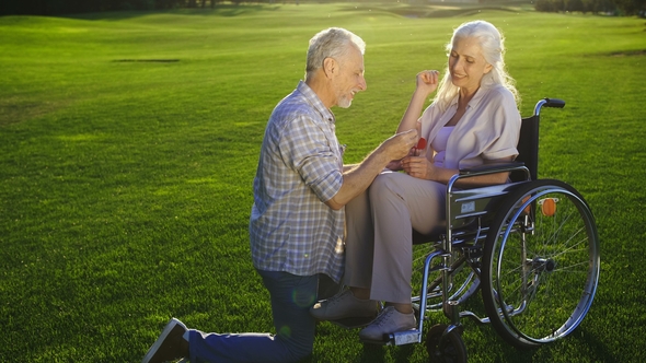 Senior Man on Knee Proposing Woman on Wheelchair