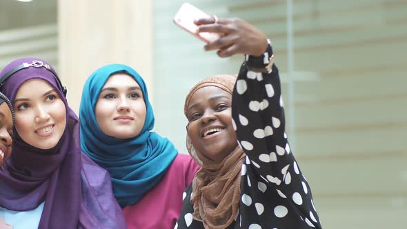 Group of Four Multiethnic Muslim Women in Traditional Hijab Take Selfie in Mall