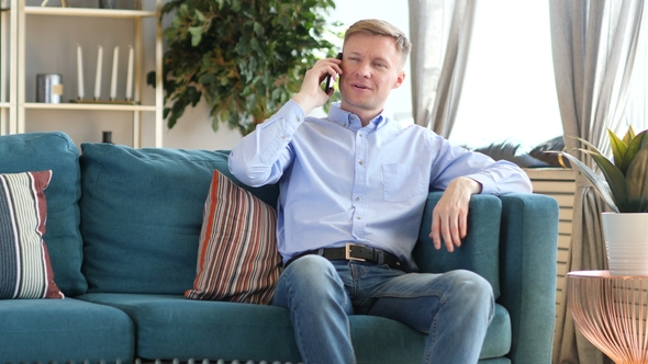 Middle Aged Man Talking on Phone, Sitting on Couch