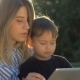 Young Mother with a Child and a Tablet on a Park Bench - VideoHive Item for Sale