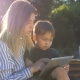 Child with Tablet and Mother on a Bench in the Park - VideoHive Item for Sale