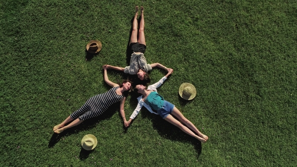 Three Attractive Girls Lying on Green Grass and Having Fun on a Meadow Sunny Day and Background of