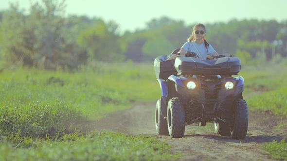 Little Girl Sits Behind the Wheel of ATV and Rides Off-road