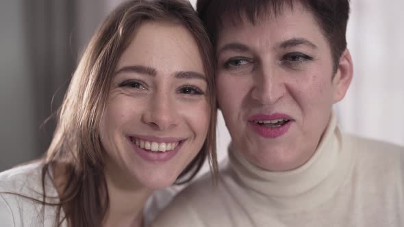 Portrait of Happy Caucasian Mother and Daughter Looking at Camera and Smiling. Cheerful Young Woman