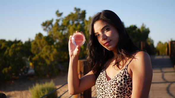 A dreamy hispanic woman with a magic crystal ball staring and smiling in slow motion at sunset.