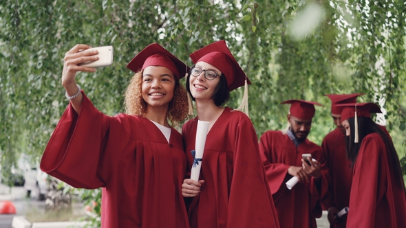 Pretty Female Graduates Are Taking Selfie with Diploma Scroll Using Smartphone, Young Women Are