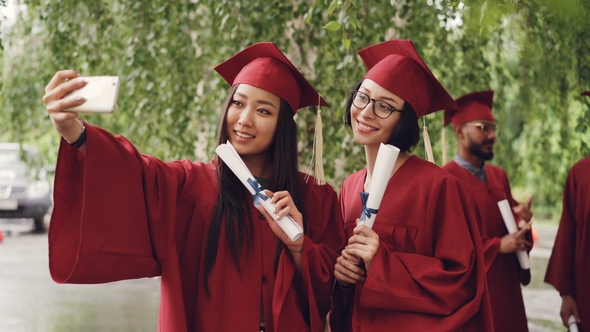 Pretty Girls Graduating Students Are Taking Selfie with Diploma Scrolls Using Smartphone, Women Are