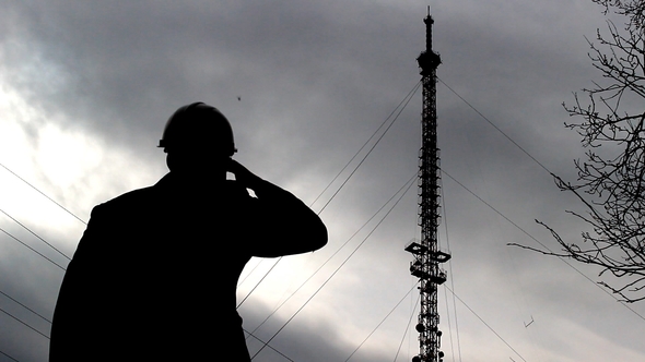 Inspector in a Protective Helmet Examines the Telephone Tower