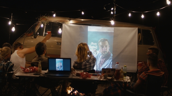 Friends Watching Movie on Screen in Campsite