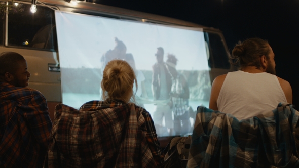 Friends Watching Movie on Screen in Campsite