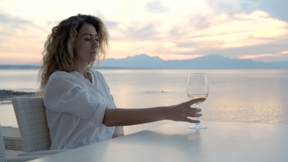 A Young Woman Sitting on the Beach and Meets a Sunset