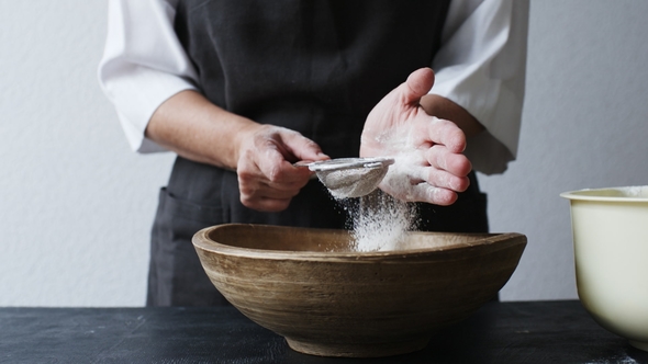 Female Hands Sifting Flour By Bowl