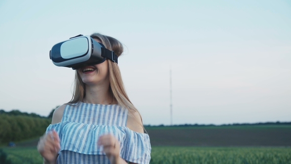 Pretty Girl in Virtual Reality Goggles Headset Immitating in the Field