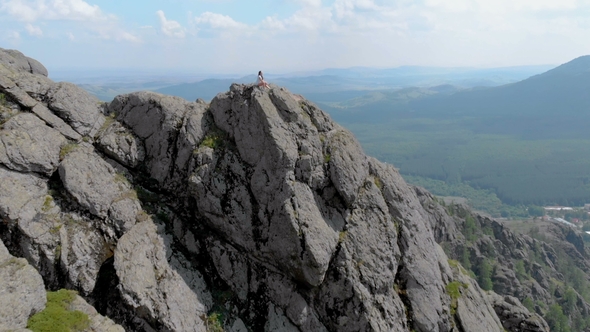 A Young Woman Is Sitting on the Edge of an Impressive Mountains Mountain Cliff