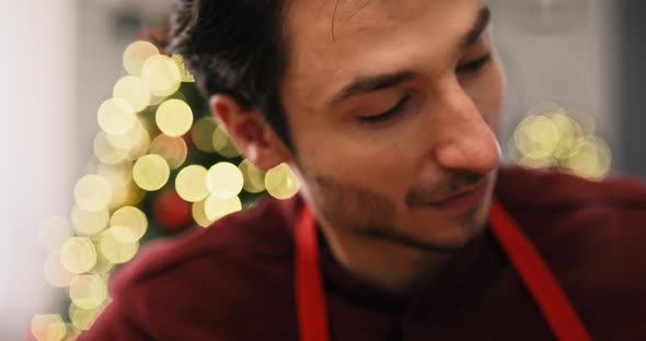 Handheld video shows of man decorating cookies in the kitchen