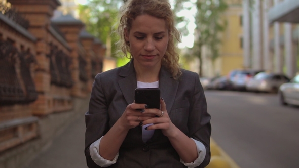 Charming Woman Going Along the Street and Using Her Mobile Phone