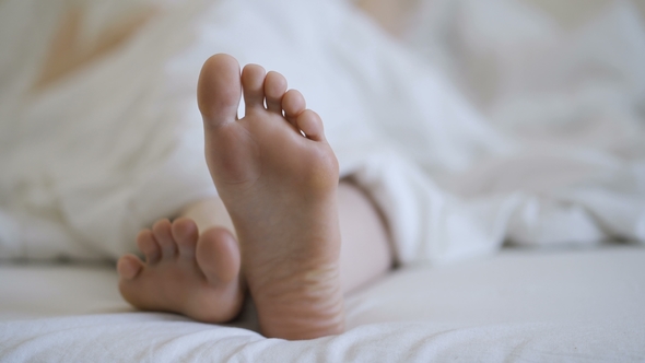 Woman in Bare Legs and Feet on the Bed