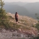 A Young Woman Approaches the Edge of the Rock and Raises Her Hands Happily - VideoHive Item for Sale