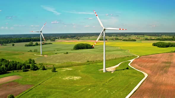 Two white wind turbines on green field in Poland, view from above