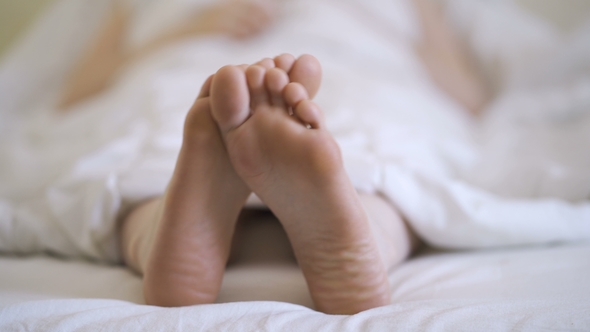 Woman in Bare Legs and Feet on the Bed