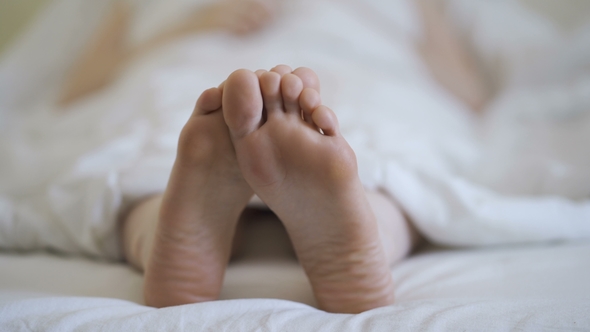 Woman in Bare Legs and Feet on the Bed