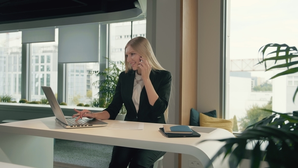 Trendy Business Woman Watching Laptop and Speaking on Phone