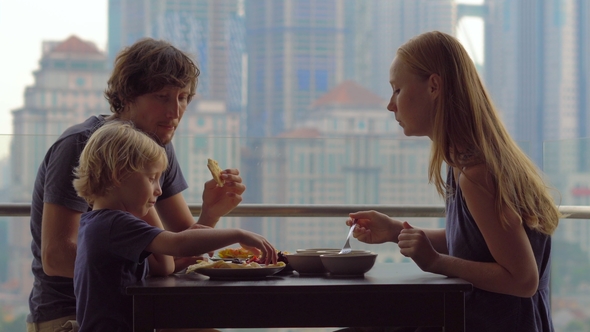 Young Family Having a Breakfast, Lunch on Their Balcony in a Skyscraper