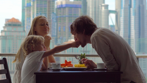 Young Family Having a Breakfast, Lunch on Their Balcony in a Skyscraper with a View on a Whole