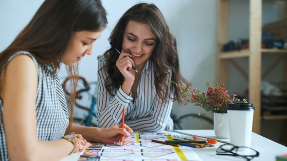 Young Female Architects Discussing with Blueprint in Office