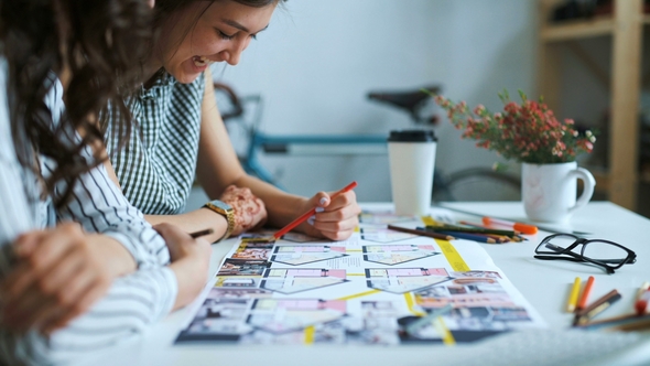 Young Female Architects Discussing with Blueprint in Office