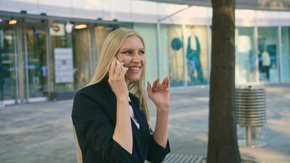 Cheerful Executive Woman Waving with Hand. Adult Blond Businesswoman in Suit Sitting on Bench 