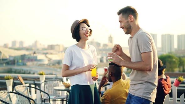 Man and Woman Are Chatting at Open-air Party Then Greeting Their Friend Hipster Hugging, Shaking
